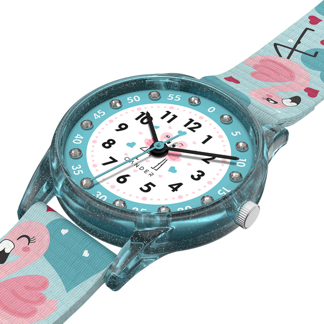 Eine Kinder-Armbanduhr mit einem türkisem Stoffarmband, auf dem super süße Flamingos abgebildet sind. Das türkis-transparentem Gehäuse hat ein Glitzereffekt. Auf dem Ziffernblatt befinden sich kleine Schmucksteine. Die Zahlen auf dem türkis- weißem Ziffernblatt sind sehr gut ablesbar.
