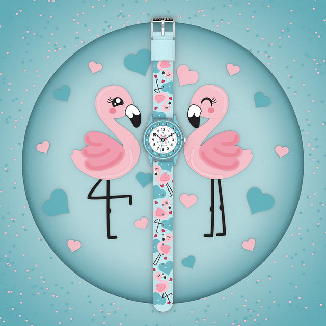 Eine Kinder-Armbanduhr mit einem türkisem Stoffarmband, auf dem super süße Flamingos abgebildet sind. Das türkis-transparentem Gehäuse hat ein Glitzereffekt. Auf dem Ziffernblatt befinden sich kleine Schmucksteine. Die Zahlen auf dem türkis- weißem Ziffernblatt sind sehr gut ablesbar.